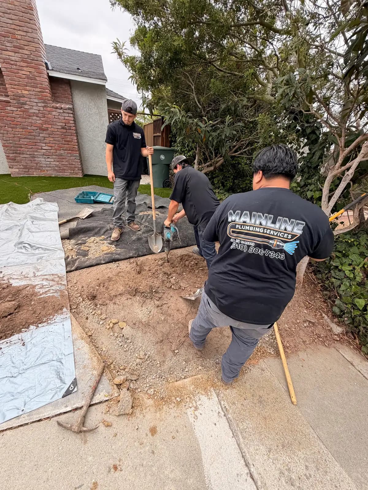 Mainline Plumbing crew in branded shirts performing a trenchless sewer line replacement in a South Bay front yard